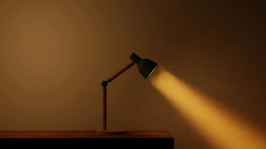 A minimalist desk lamp casting a warm beam of light on a wooden surface.